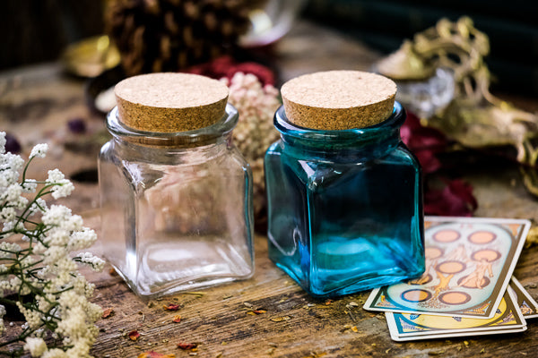 One clear and one blue apothecary jar on display with corks.