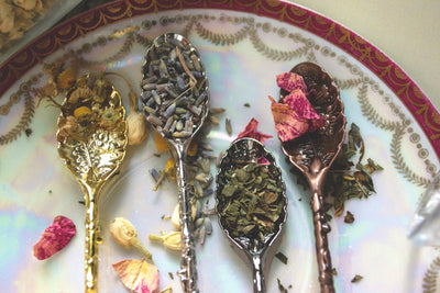 Variety of crystal spoons laid on a plate. Gold, silver, pewter, and brass.