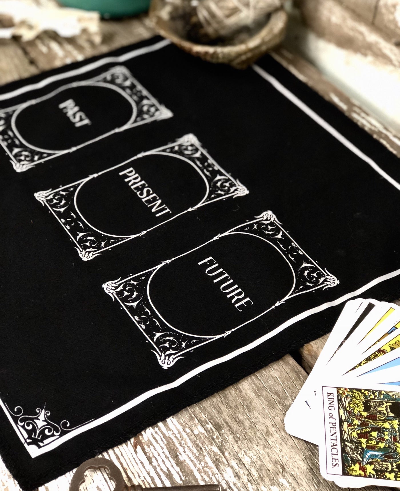 Photo of three card tarot cloth. Black with white lettering. 