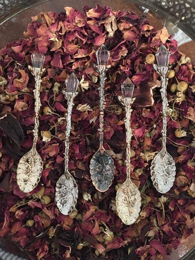 Close up of five different tea spoons with a single crystal on top