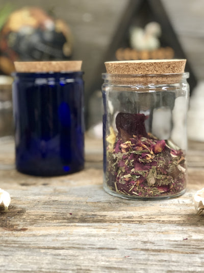 One clear and one blue round 12 oz apothecary jar displayed with corks.